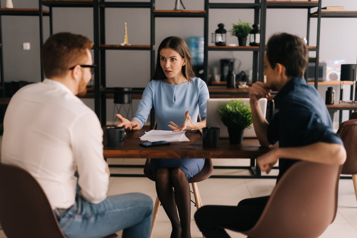 Woman Real Estate Agent meeting with young couple in real estate agency office.