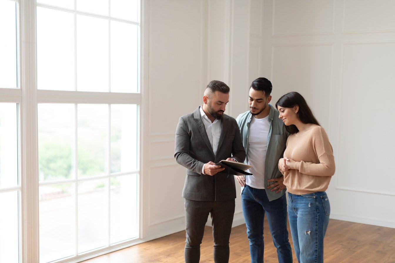 Couple Buying New Apartment, House Agent Showing Documents Blueprints